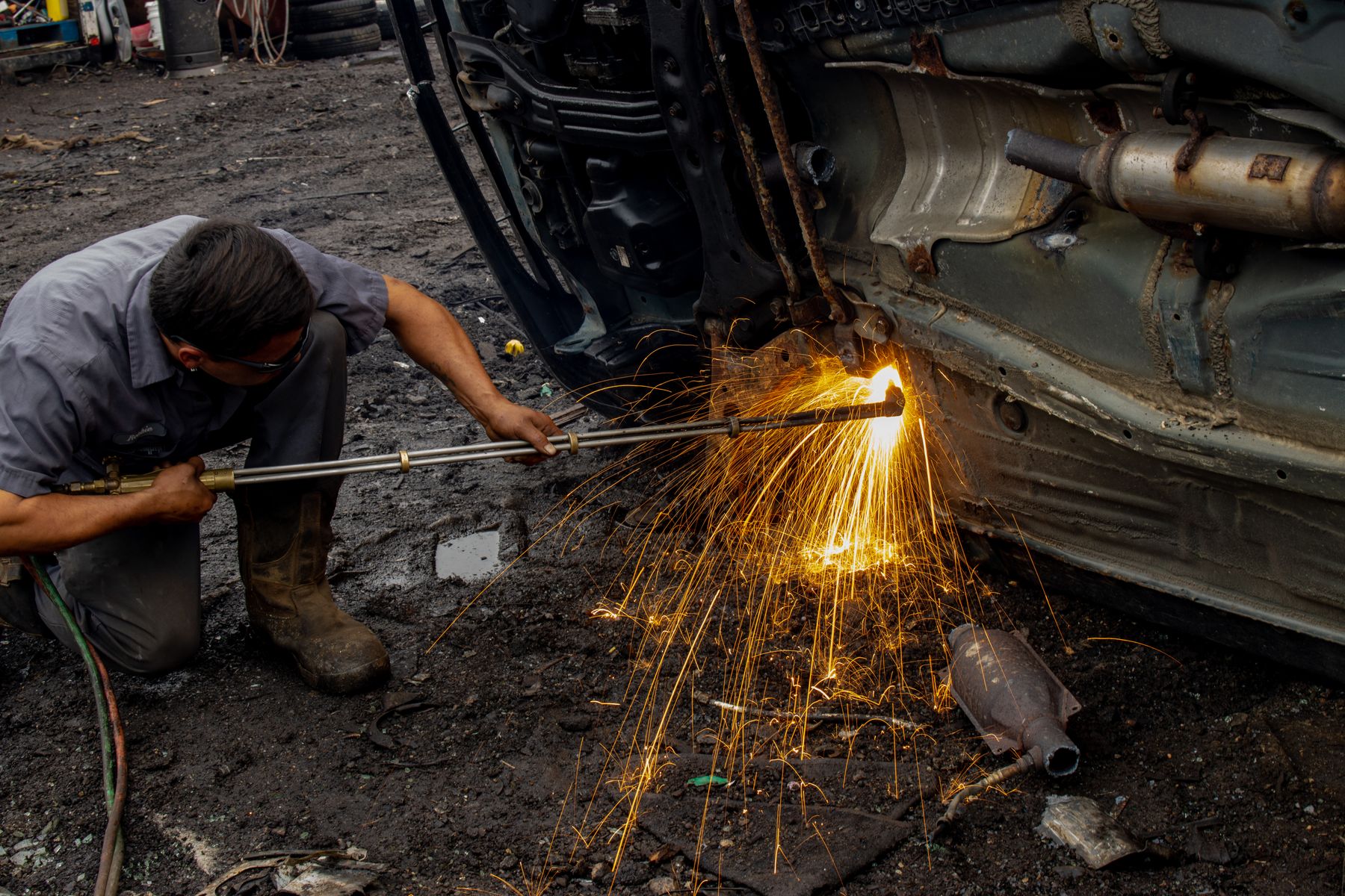 Panel beater welding a car body with sparks flying